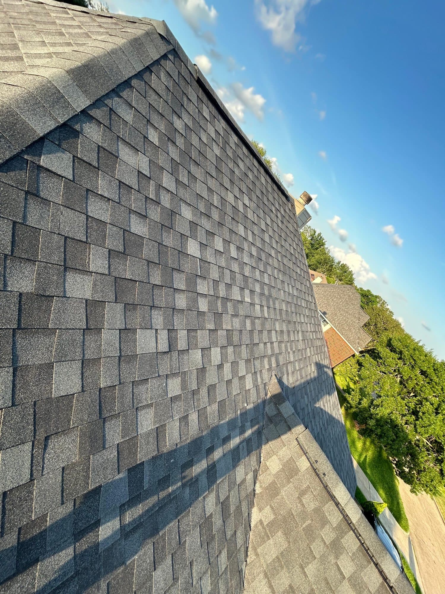 Grey architectural shingles running up to the ridge against a clear blue Texas sky