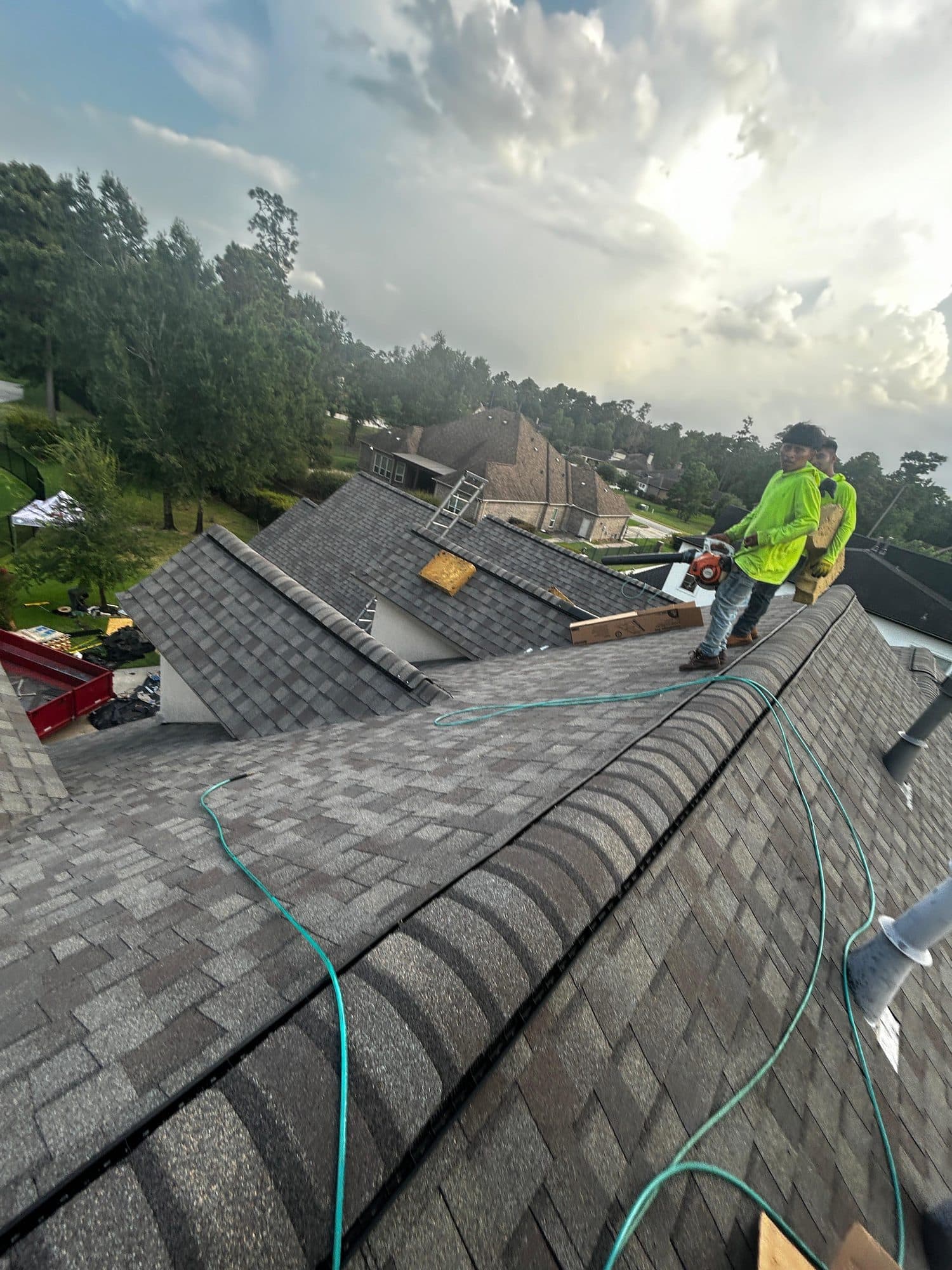 Tex-Mex Roofing crew member in a high-visibility vest working along the ridge of a shingle roof
